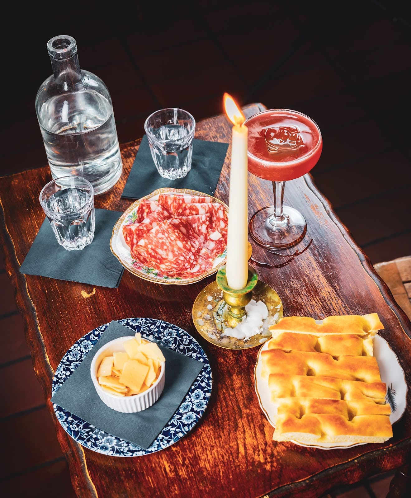 Elegant table with cocktail, salami, cheese, and candle in London