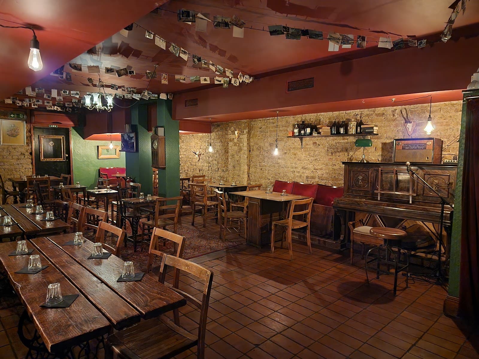 Cozy interior with wooden tables, chairs, and vintage piano in dimly lit bar in London