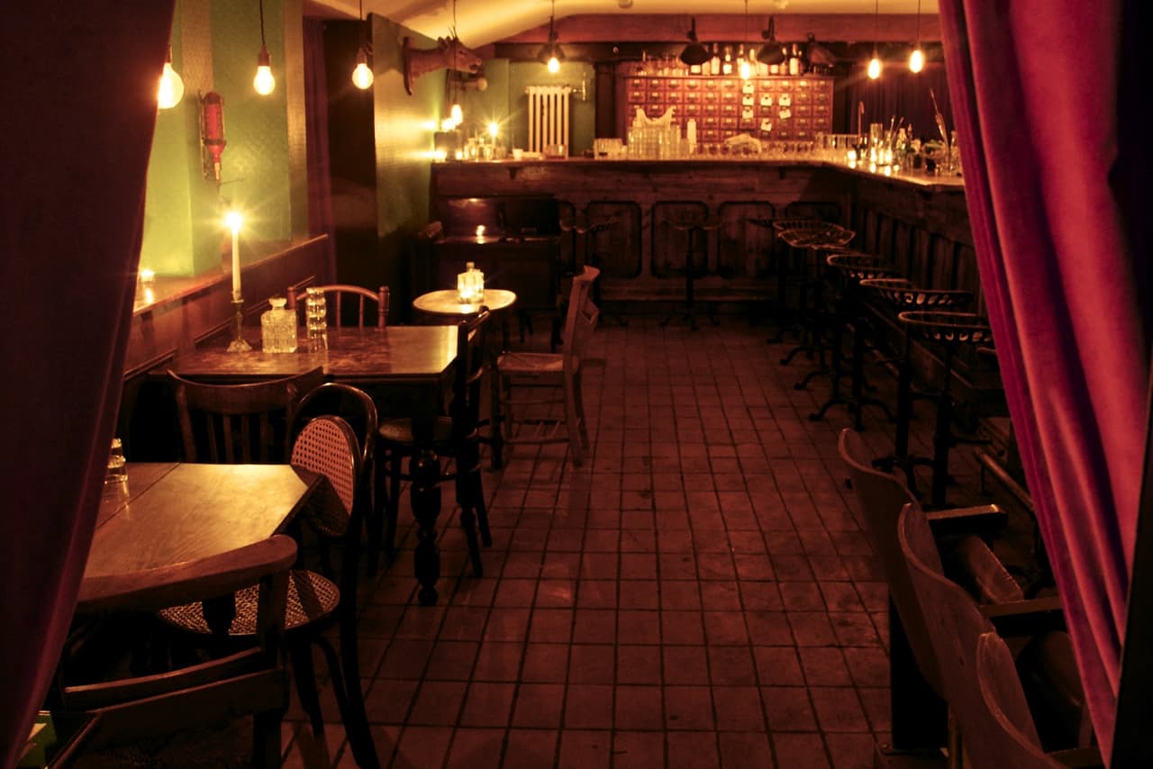 Cozy cocktail bar interior with dim lighting and wooden tables in London