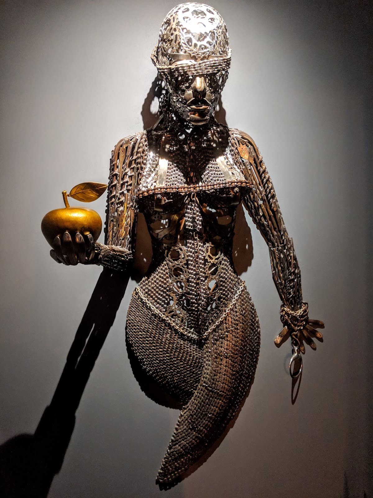 Metal sculpture of a figure holding a golden apple in London