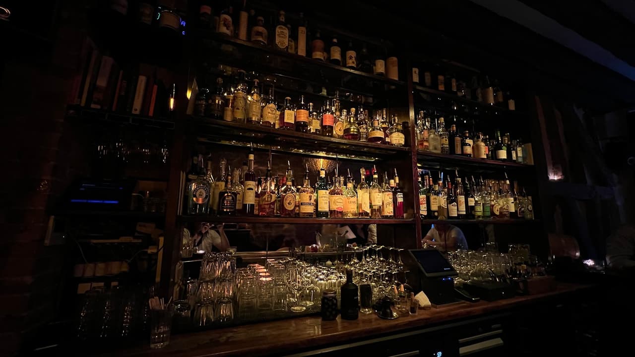 Dimly lit bar with shelves of liquor bottles and glasses in Paris