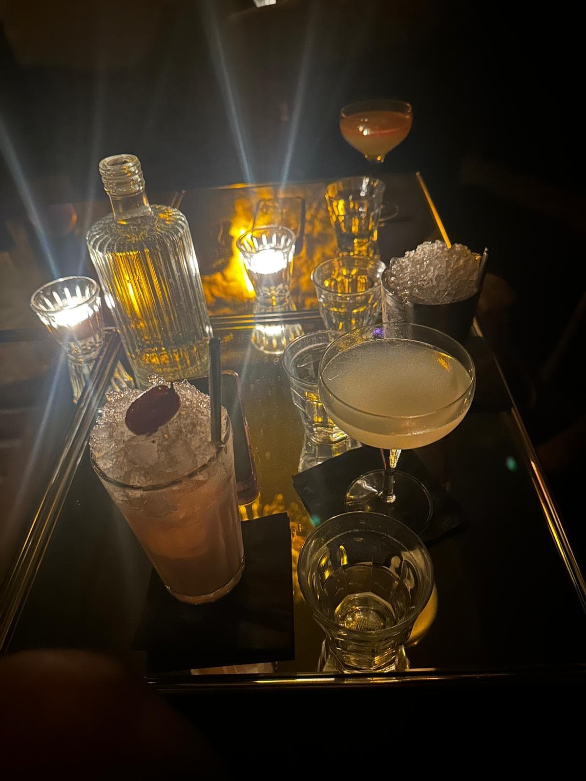 Cocktail glasses and bottle with dim lighting on a bar table in Paris
