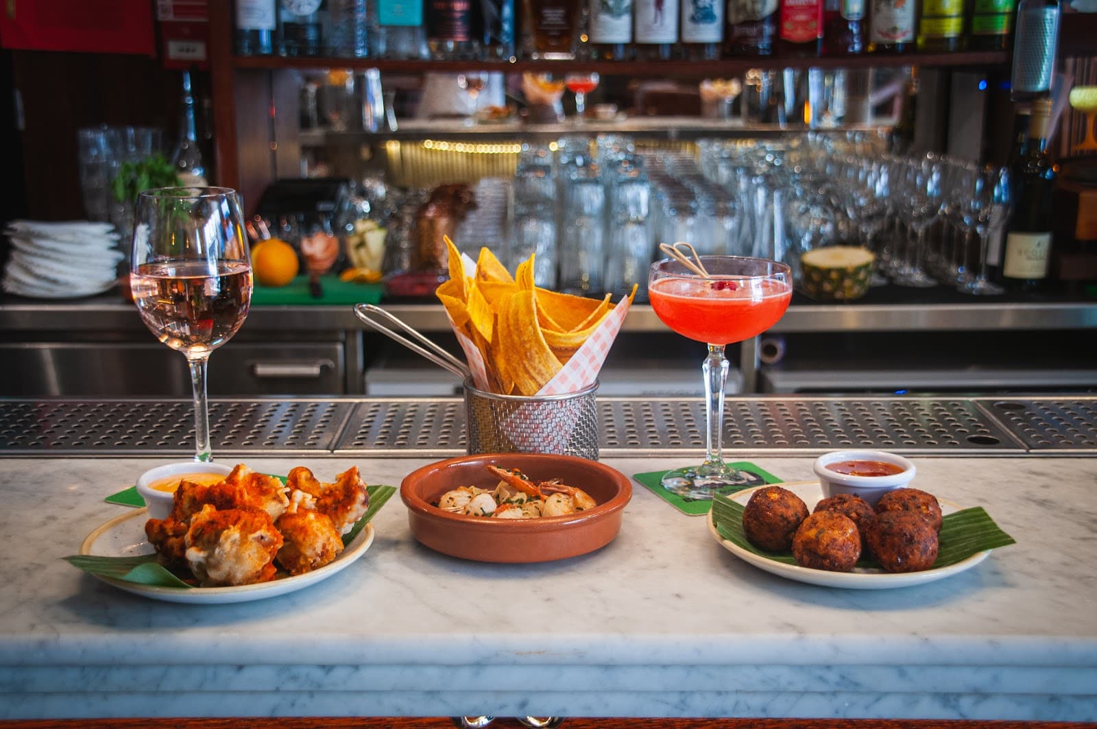 Bar counter with cocktails and small plates of food. in London