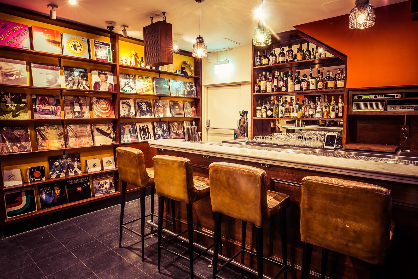 Cozy bar area with leather stools and vintage record decor. in London
