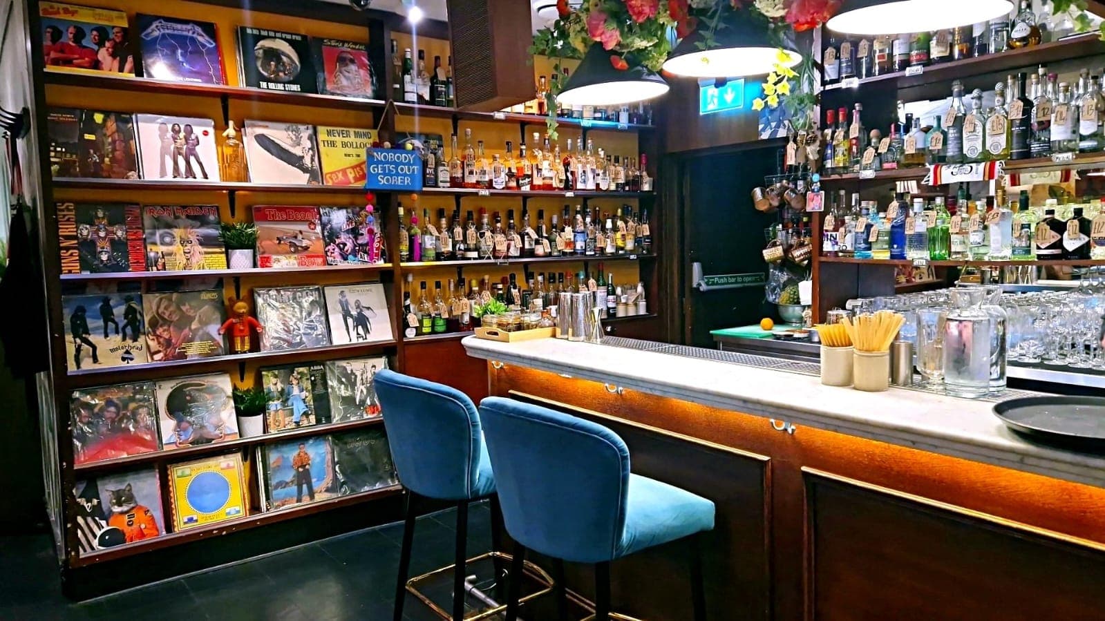 Bar counter with barstools, record covers, and bottles on shelves
