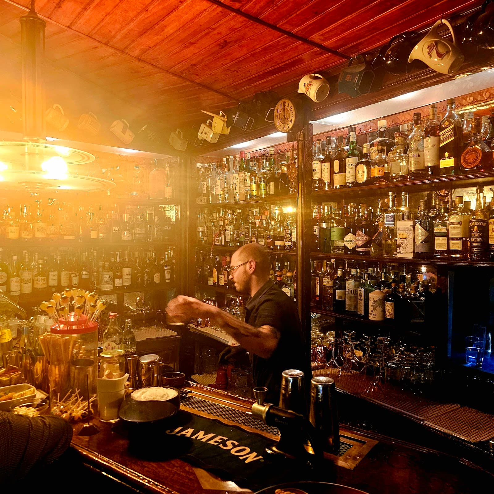Bartender working behind a well-stocked bar in dim lighting in Lisboa