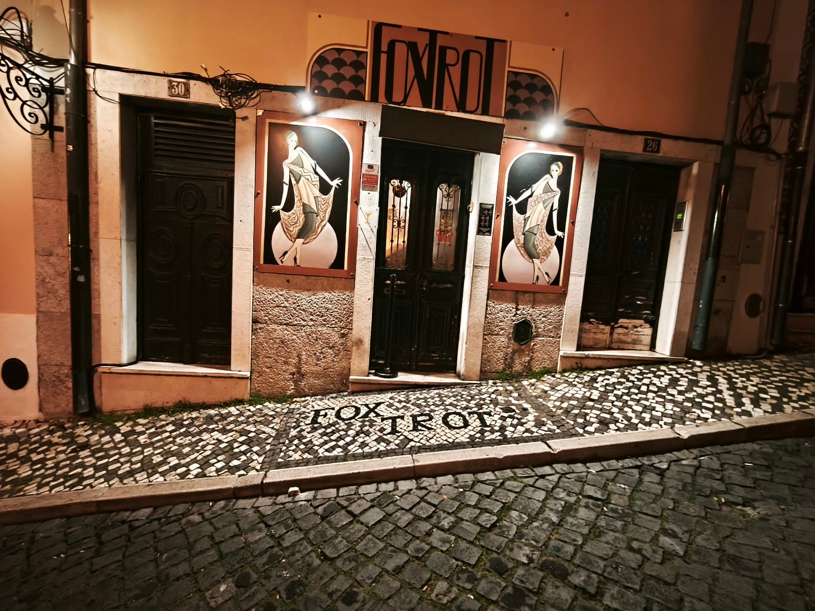 Exterior of Fox Trot bar with artistic door panels and cobblestone path in Lisboa