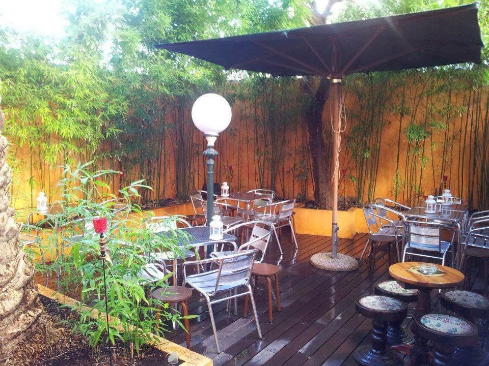 Outdoor patio with metal chairs, wooden flooring, and greenery