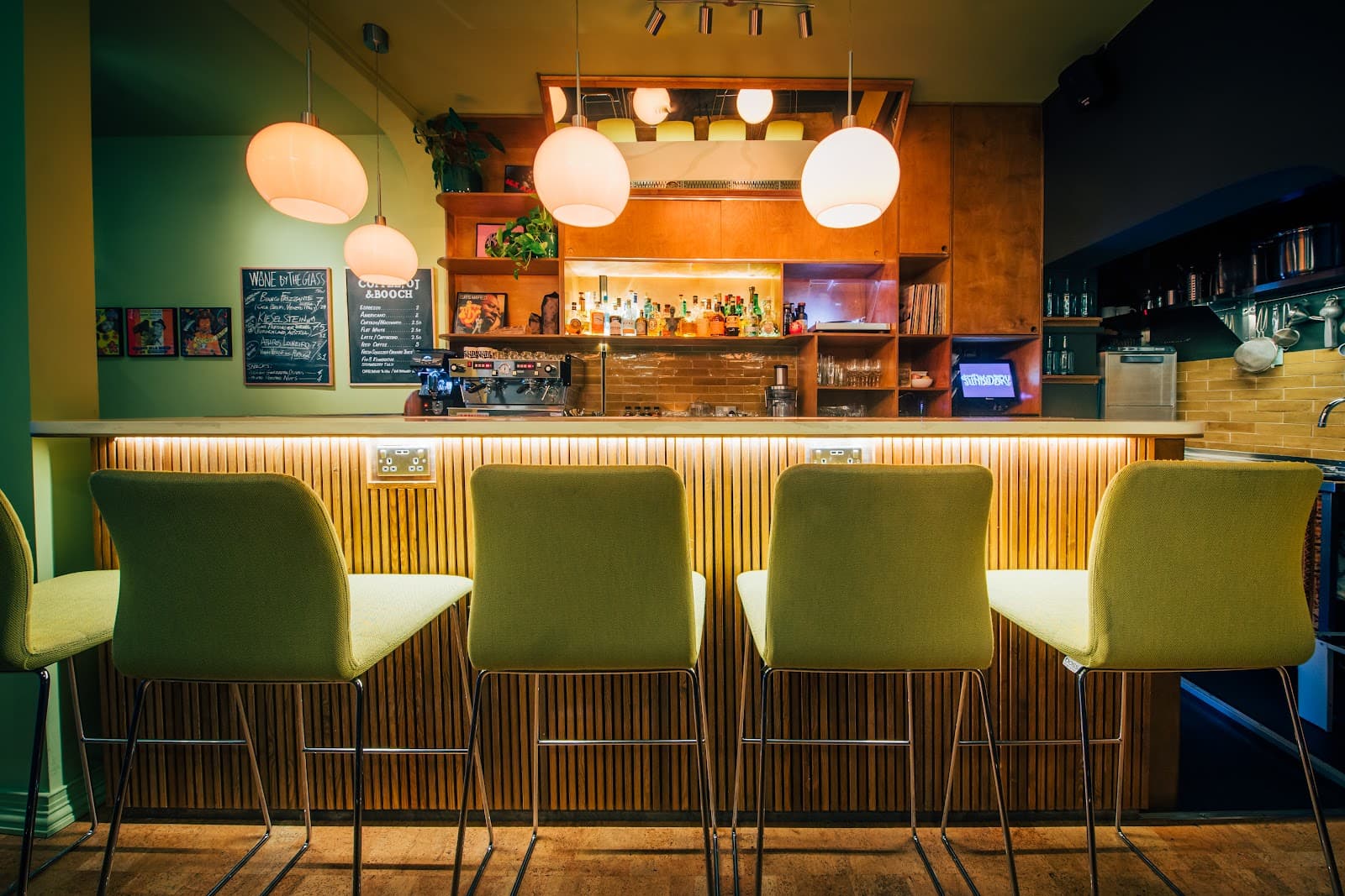 Stylish bar interior with green chairs and illuminated shelving