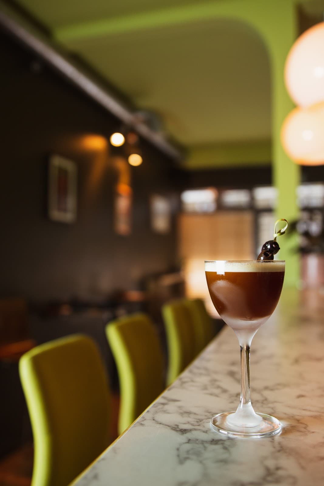 Cocktail glass on a marble bar counter with a blurred bar background in London