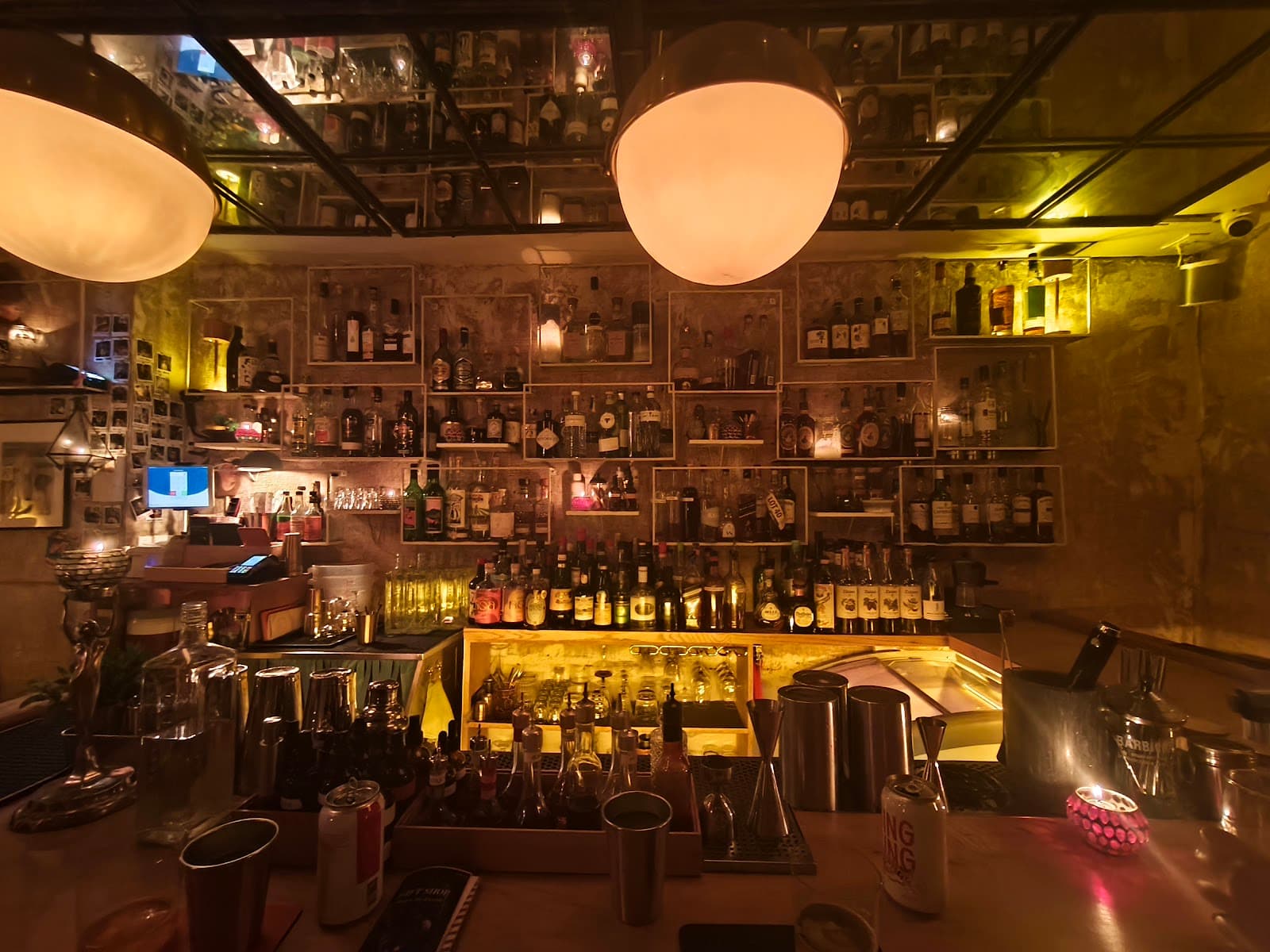 Cozy bar with warm lighting, shelves of bottles, and cocktails in the foreground