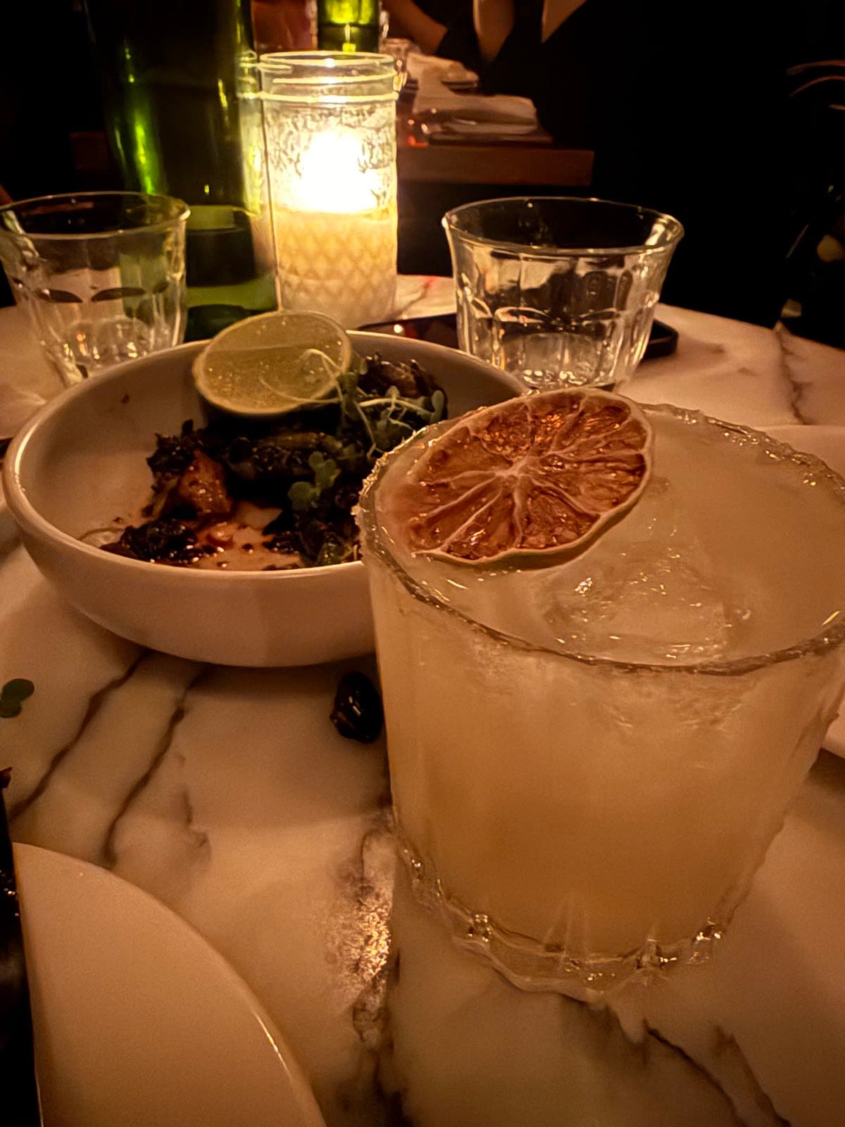 Cocktail with dried citrus on marble table with candlelit atmosphere in Toronto