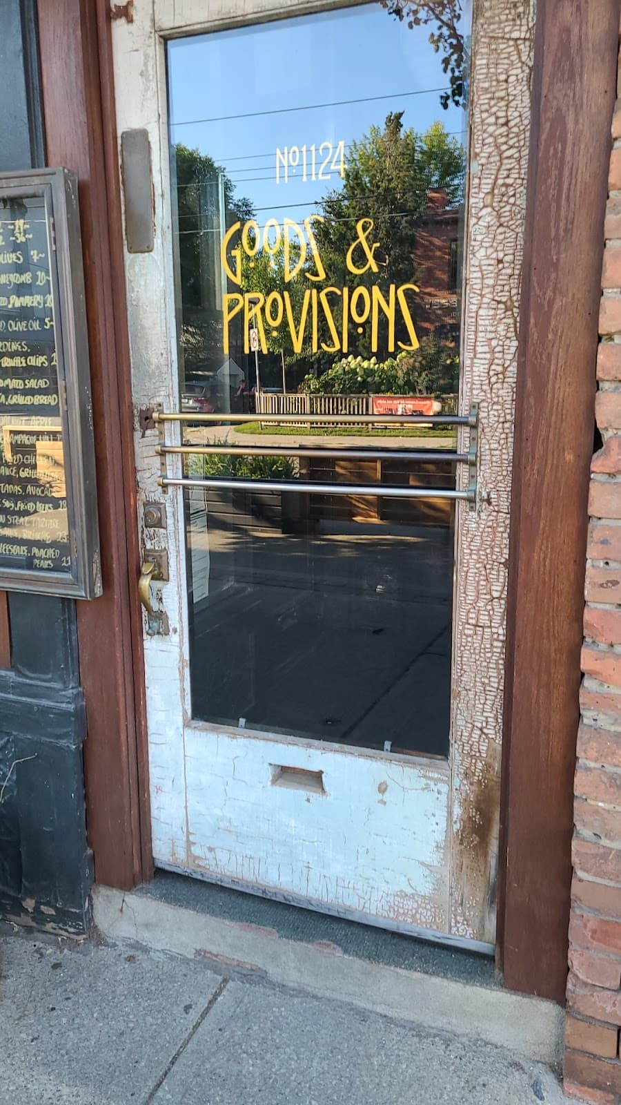 Entrance door with Goods & Provisions sign and street reflection. in Toronto