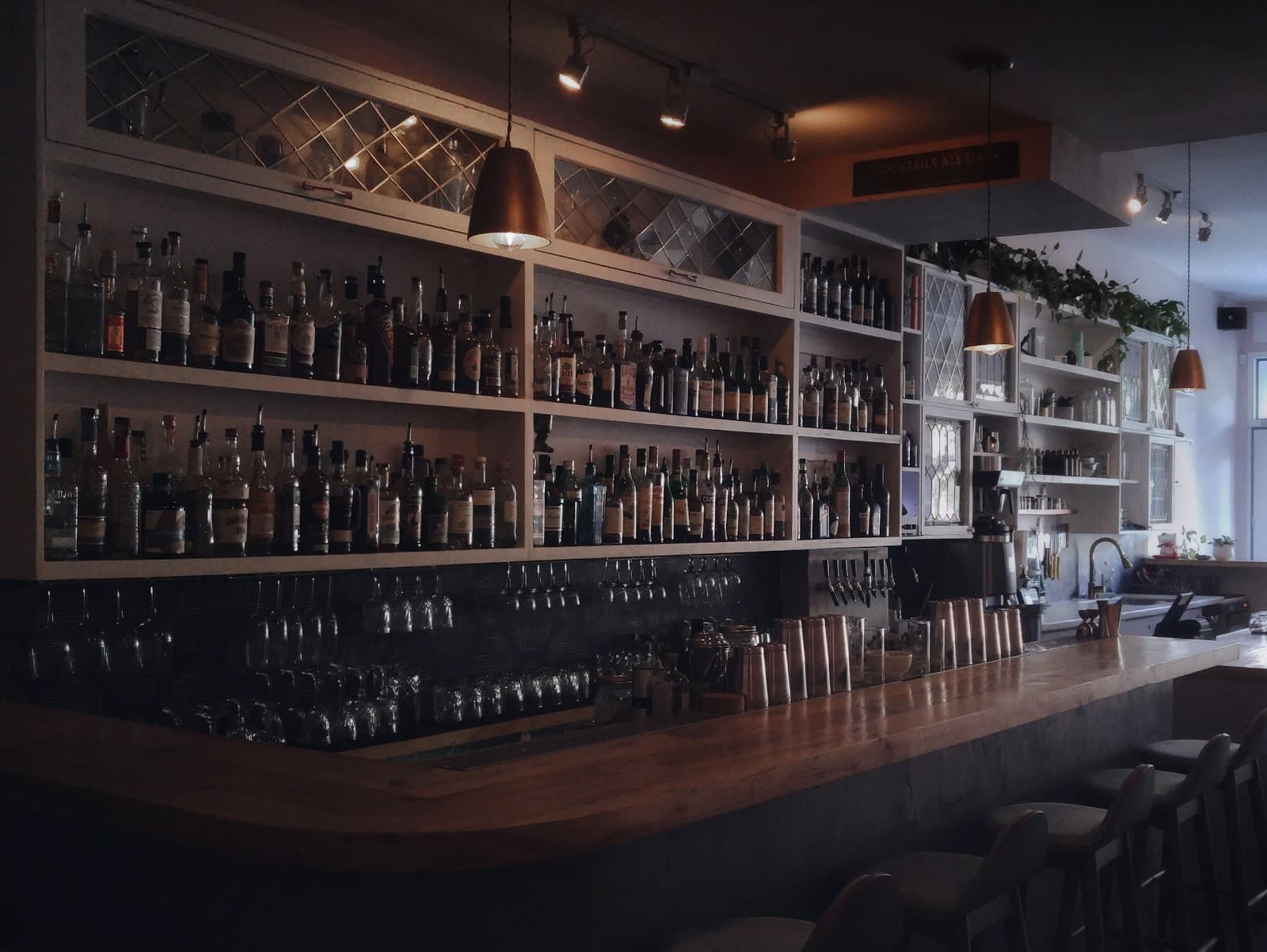 Craft cocktail bar interior with shelves of bottles and bar stools