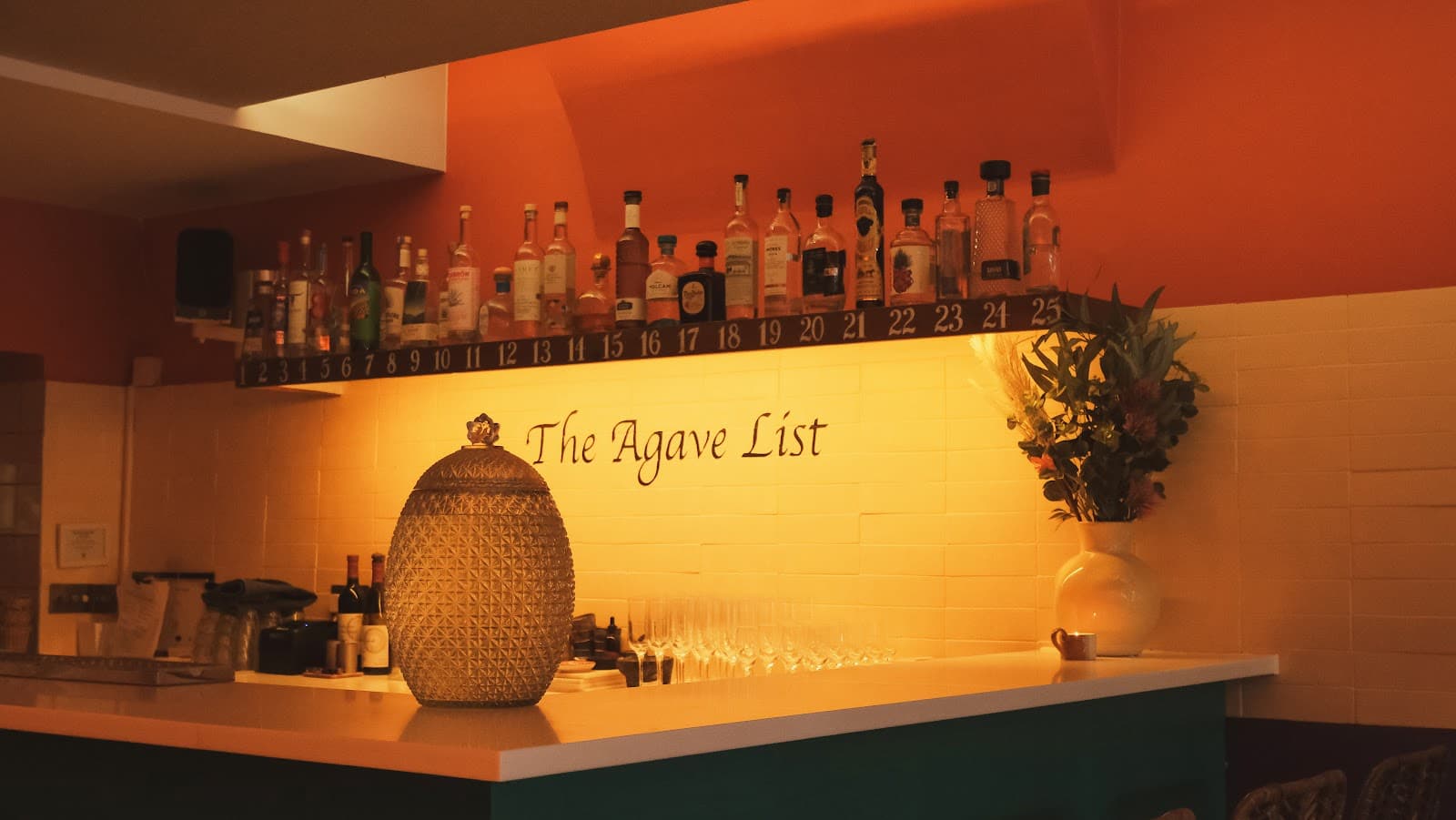 Bar counter with bottles and 'The Agave List' sign on the wall in London