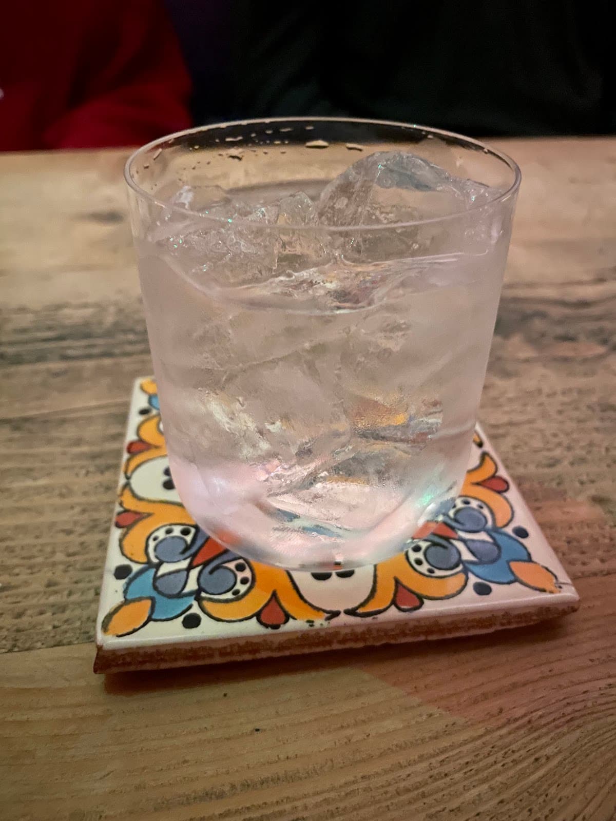 Glass of cocktail on a colorful coaster on a wooden table in London