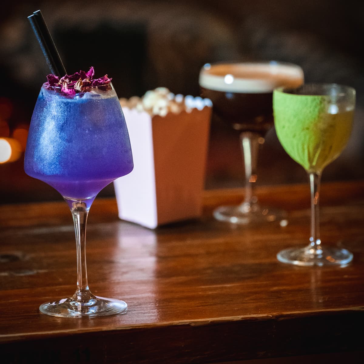 Three colorful cocktails on a wooden bar counter in Edinburgh