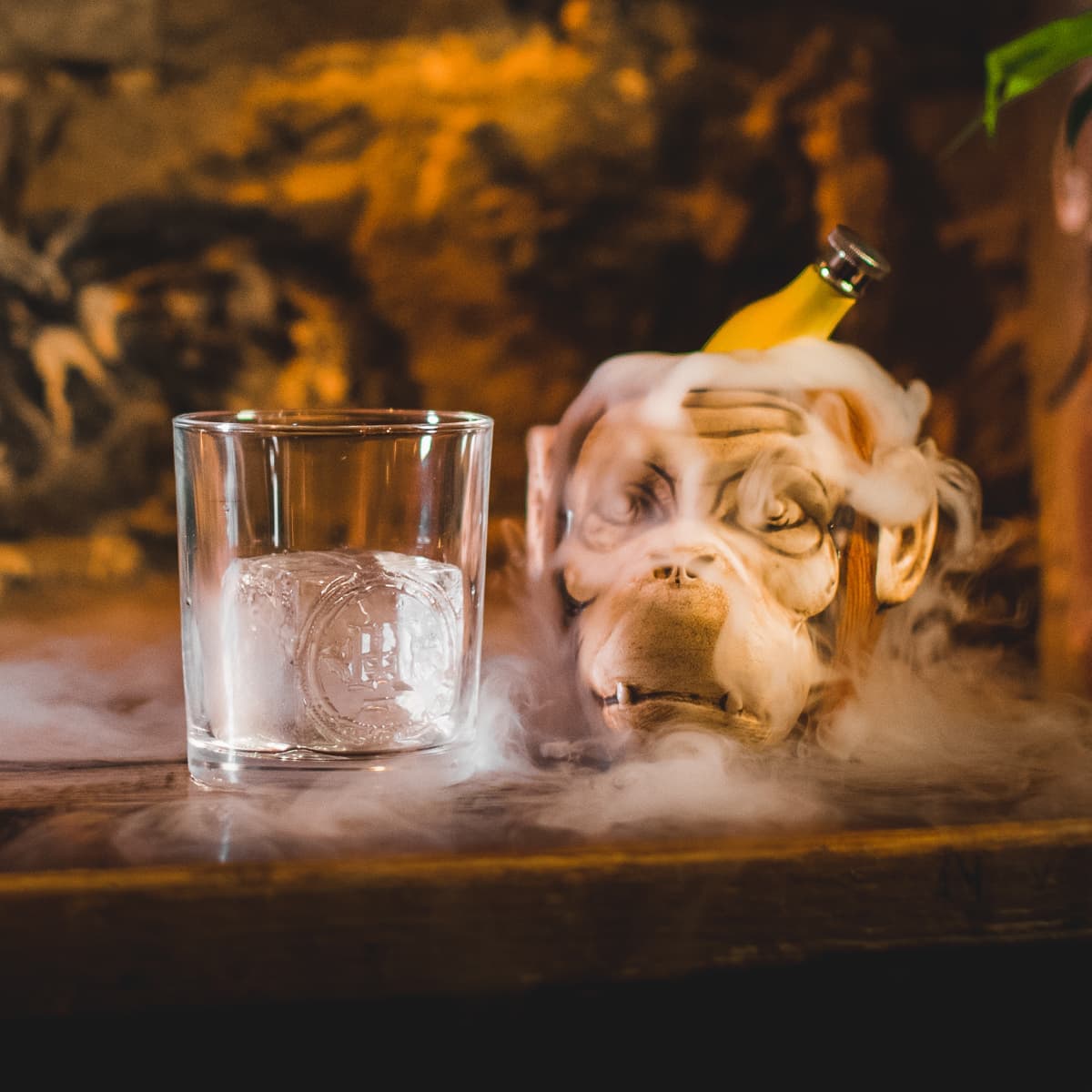 Cocktail glass with ice beside a smoke-emitting monkey statue in Edinburgh