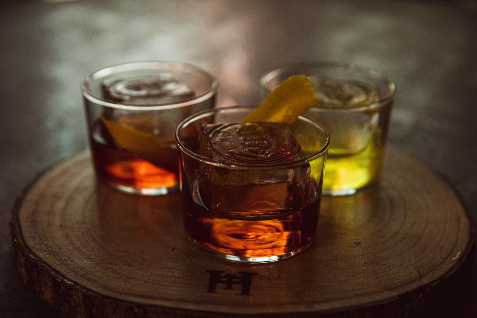 Three cocktails on a wooden slab with ice and garnish in Edinburgh