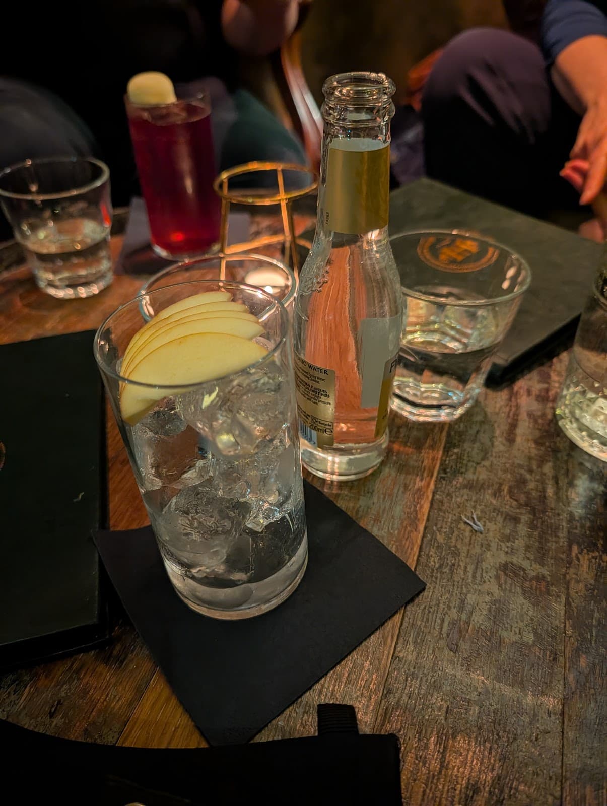 Close-up of cocktail with apple slices on a wooden table in Edinburgh