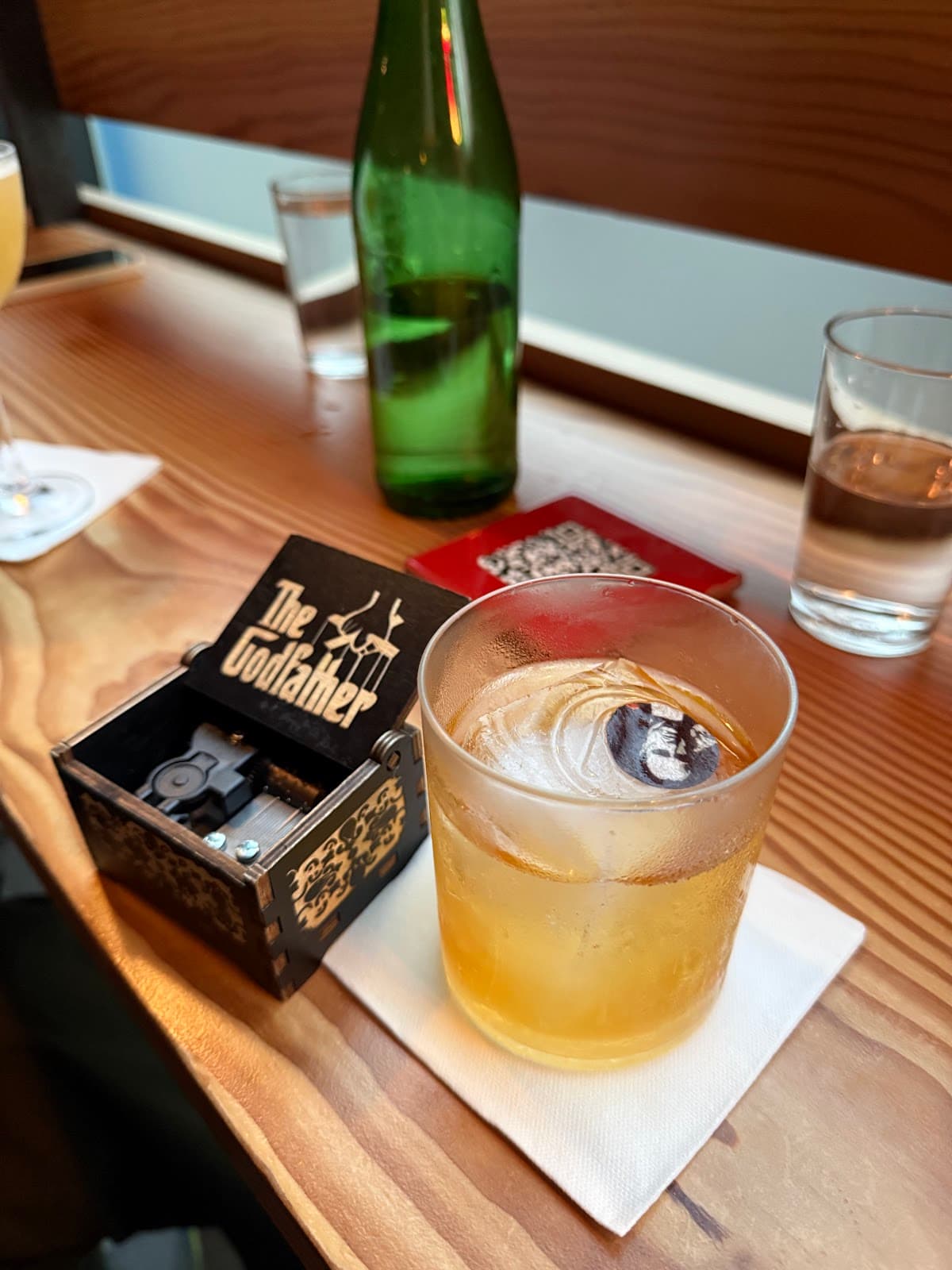 Close-up of a cocktail with a decorative ice cube and box on a wooden table in Edinburgh