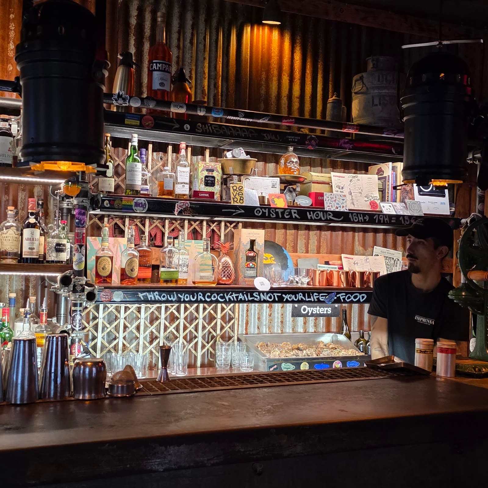 Eclectic bar counter with bottles and bartender in dimly lit setting in Lisboa