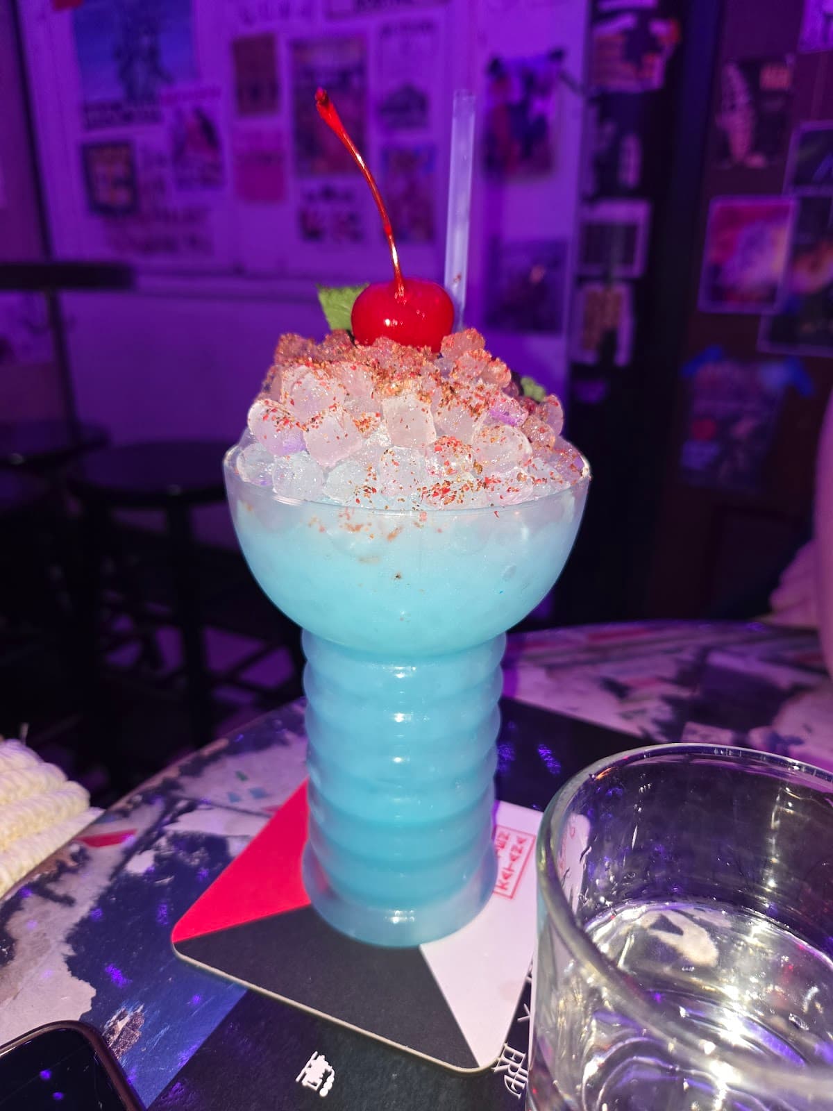 Blue cocktail in a vibrant glass with a cherry on top, bar background in New York