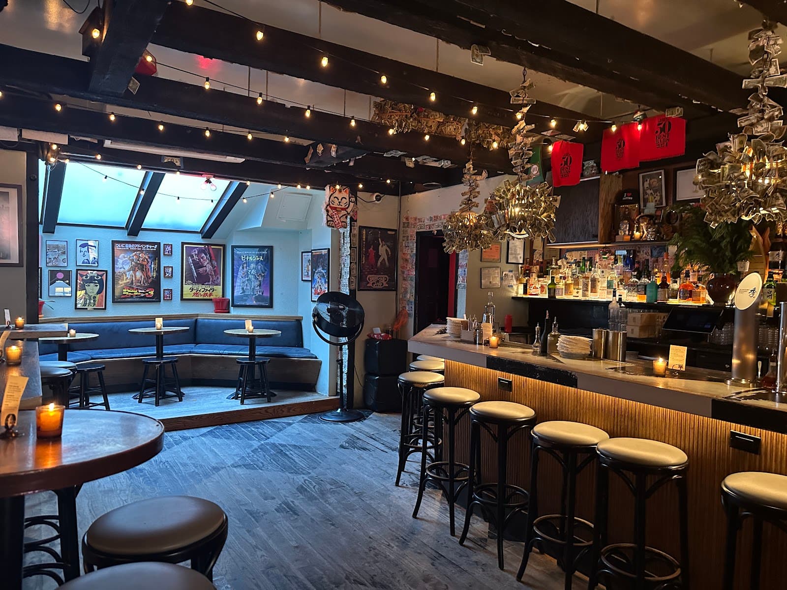 Cozy bar interior with stools, string lights, and art on walls. in New York