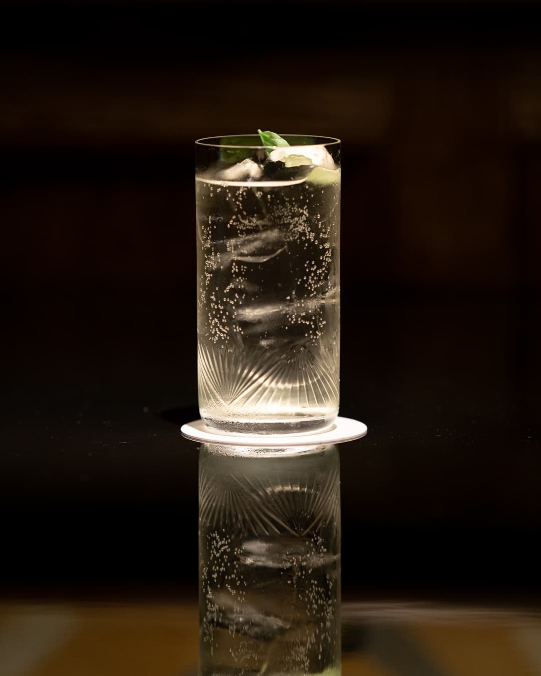 Close-up of a cocktail glass with ice and mint garnish on a dark background in London