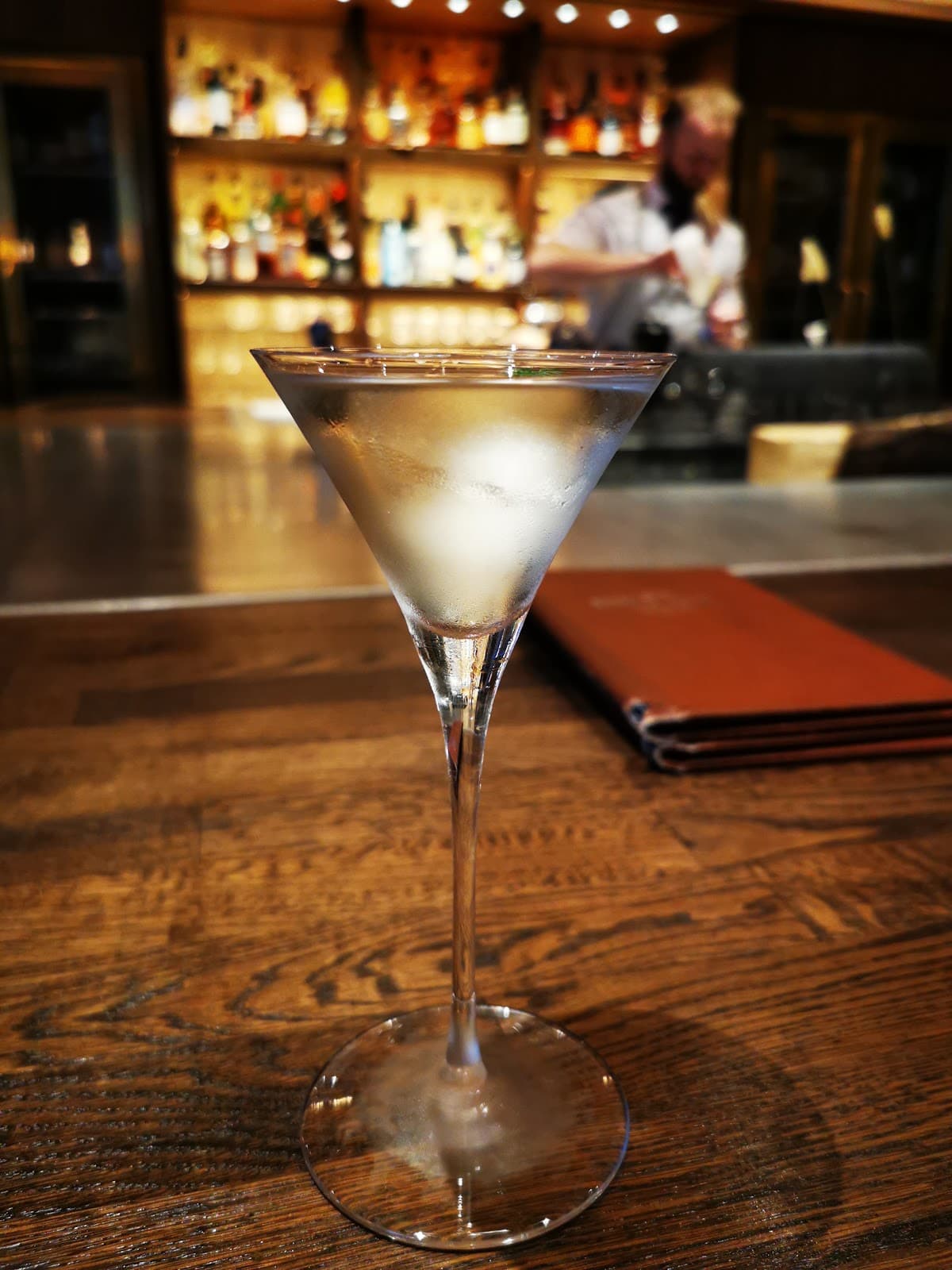 Close-up of a chilled cocktail in a martini glass on a wooden bar counter in London
