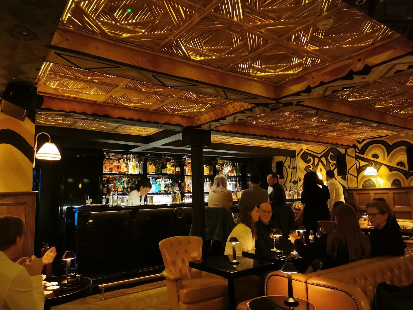 Stylish bar interior with patrons and a well-stocked bar counter in London