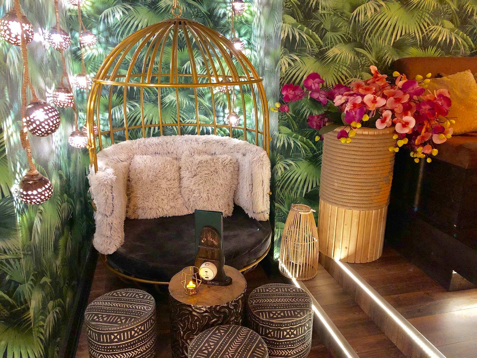 Stylish cocktail bar corner with hanging chair, plants, and soft lighting in London