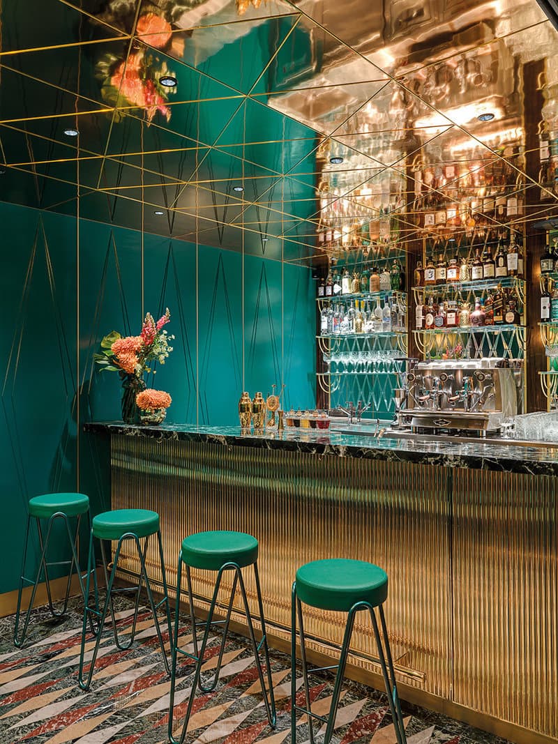 Luxurious bar area with gold accents and green stools in London