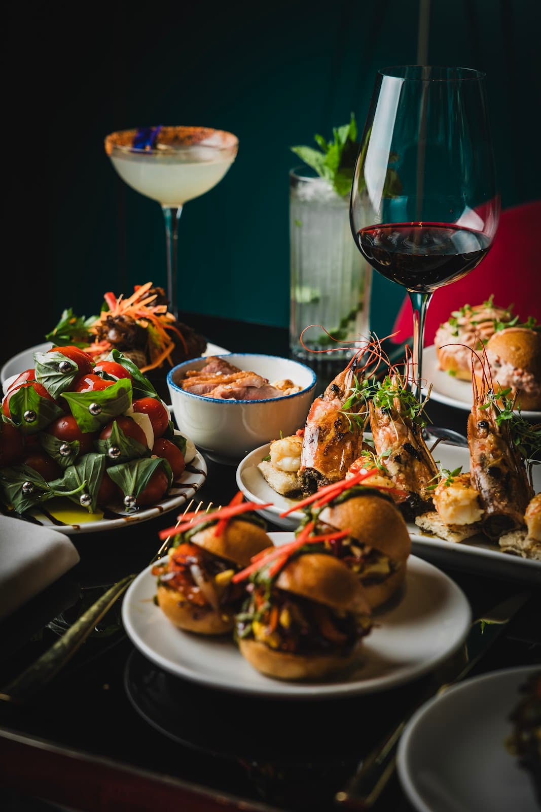 Assorted gourmet dishes with cocktails on a dark table in London