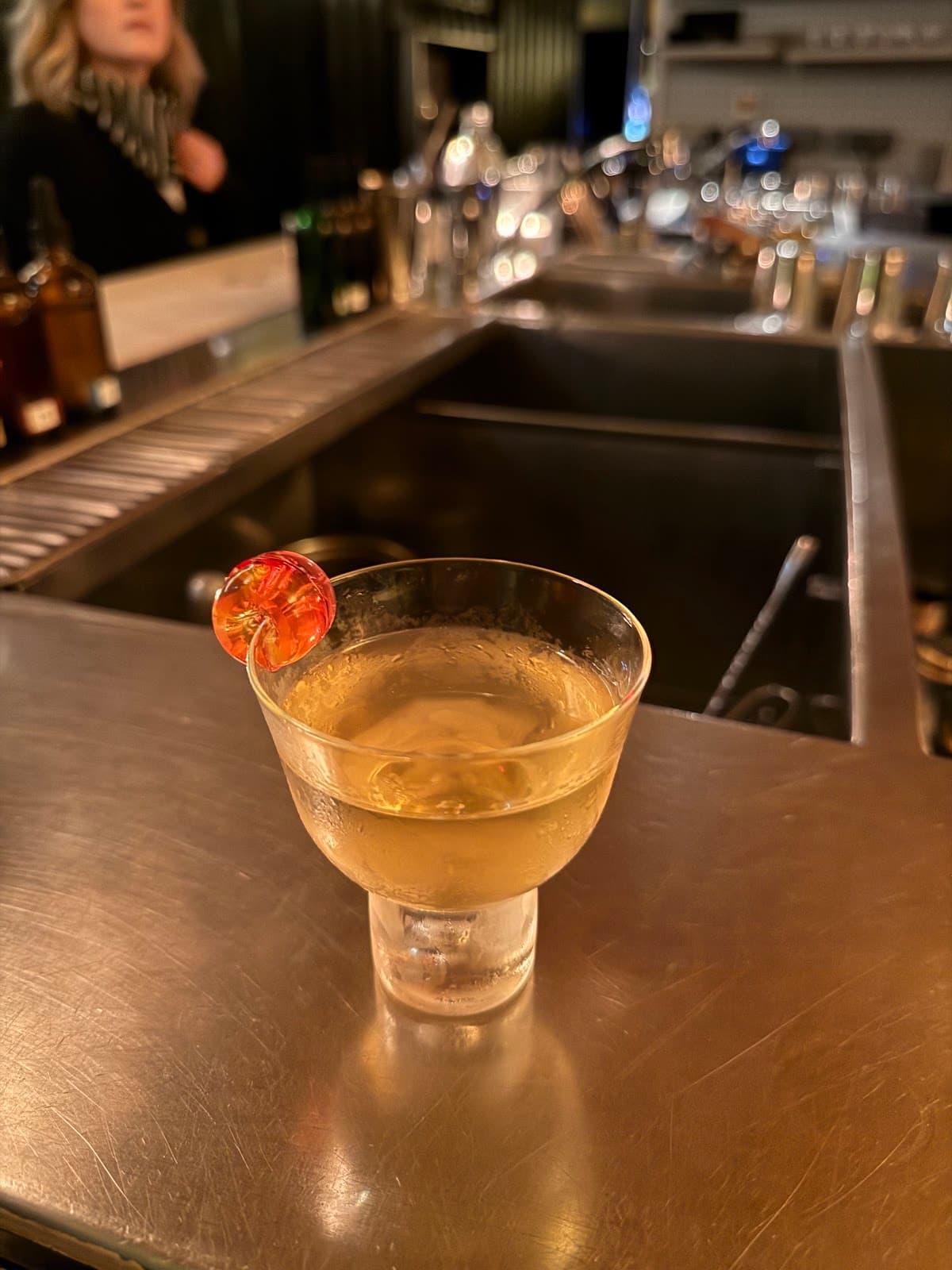 Close-up of a cocktail with orange garnish on a bar counter in Paris