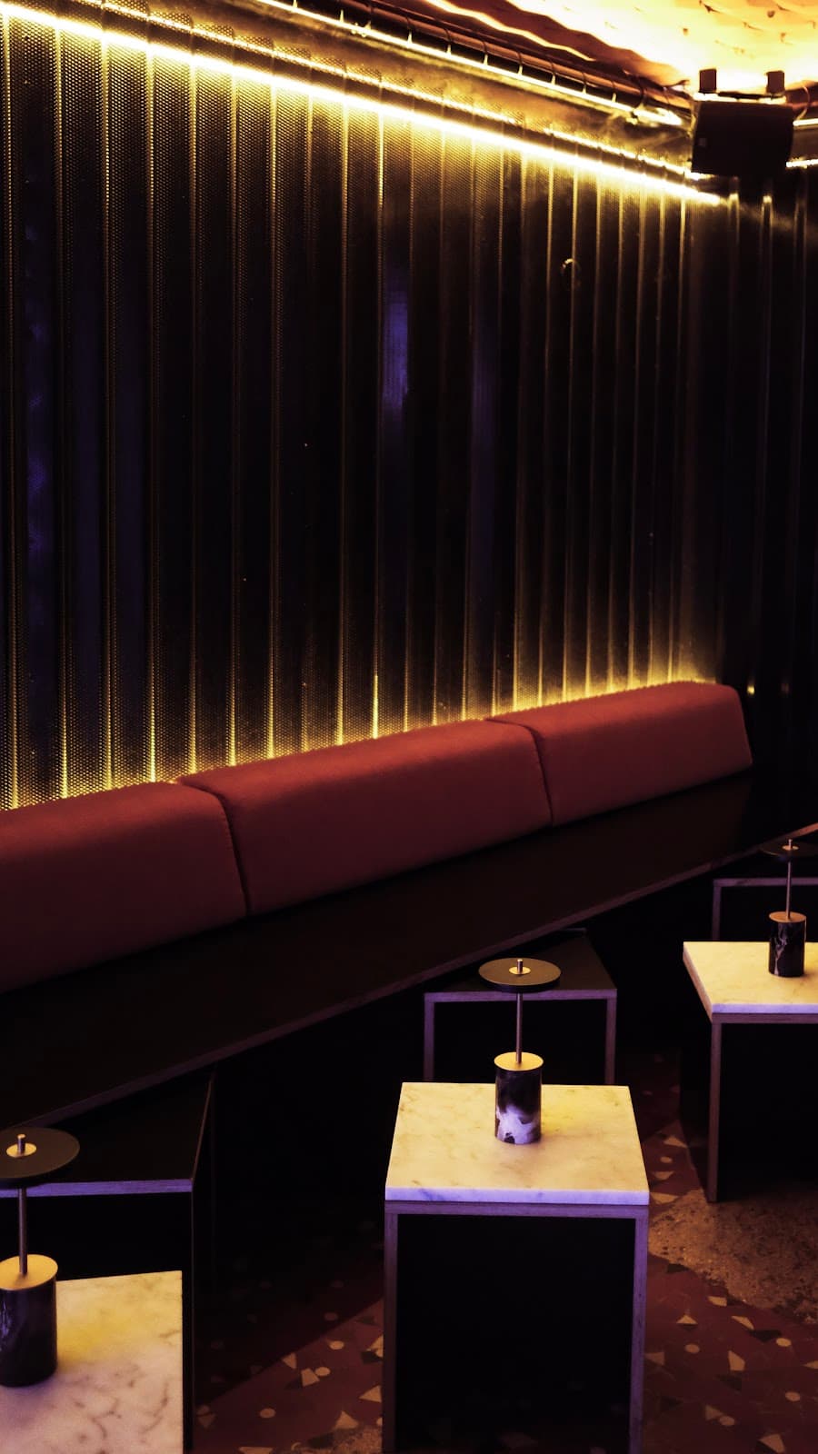 Dimly lit interior with bench seating and marble tables in Paris