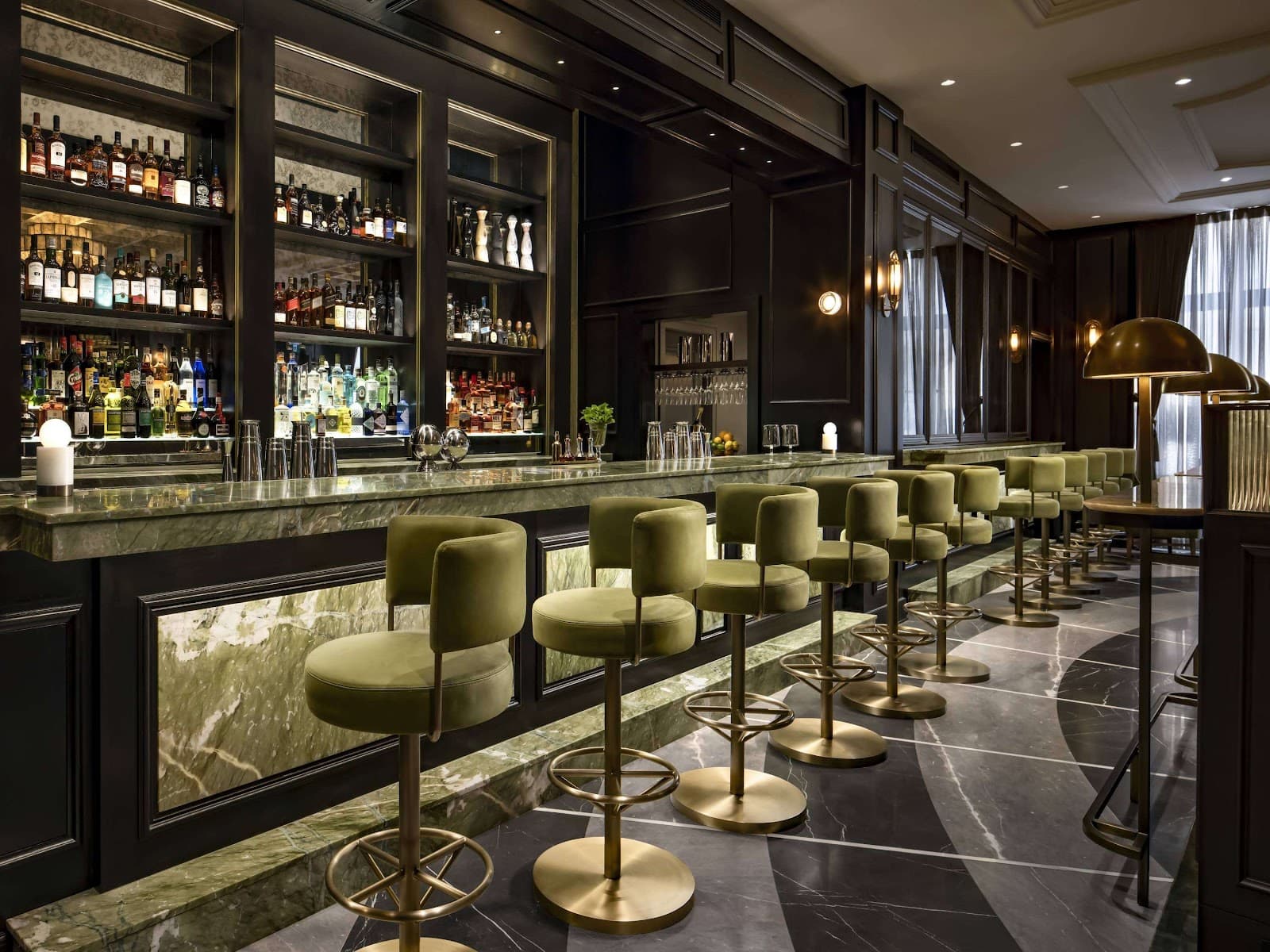 Luxurious bar interior with green velvet stools and marble counter in Toronto