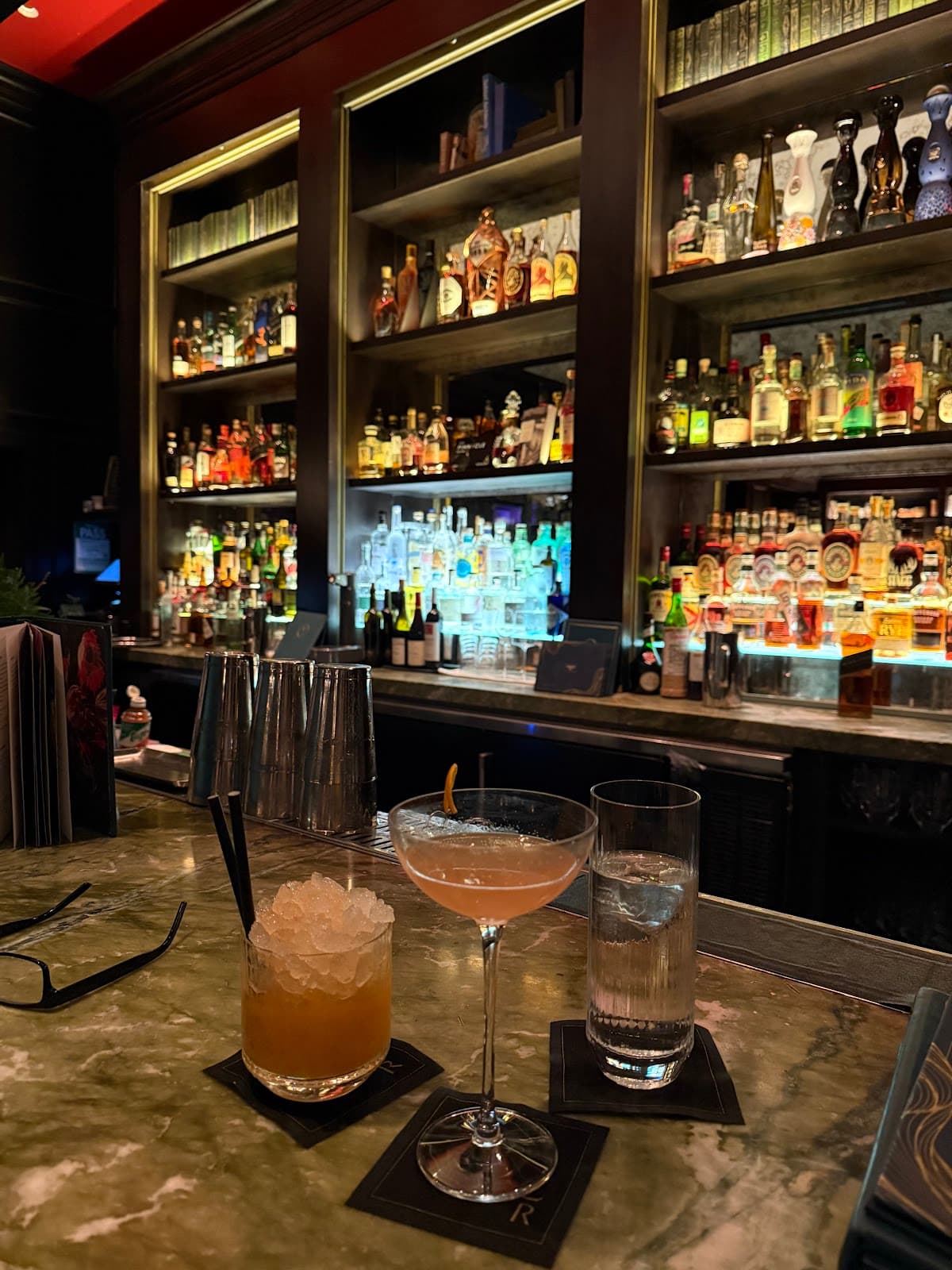 Stylish bar counter with cocktails and illuminated shelves of liquor bottles in Toronto