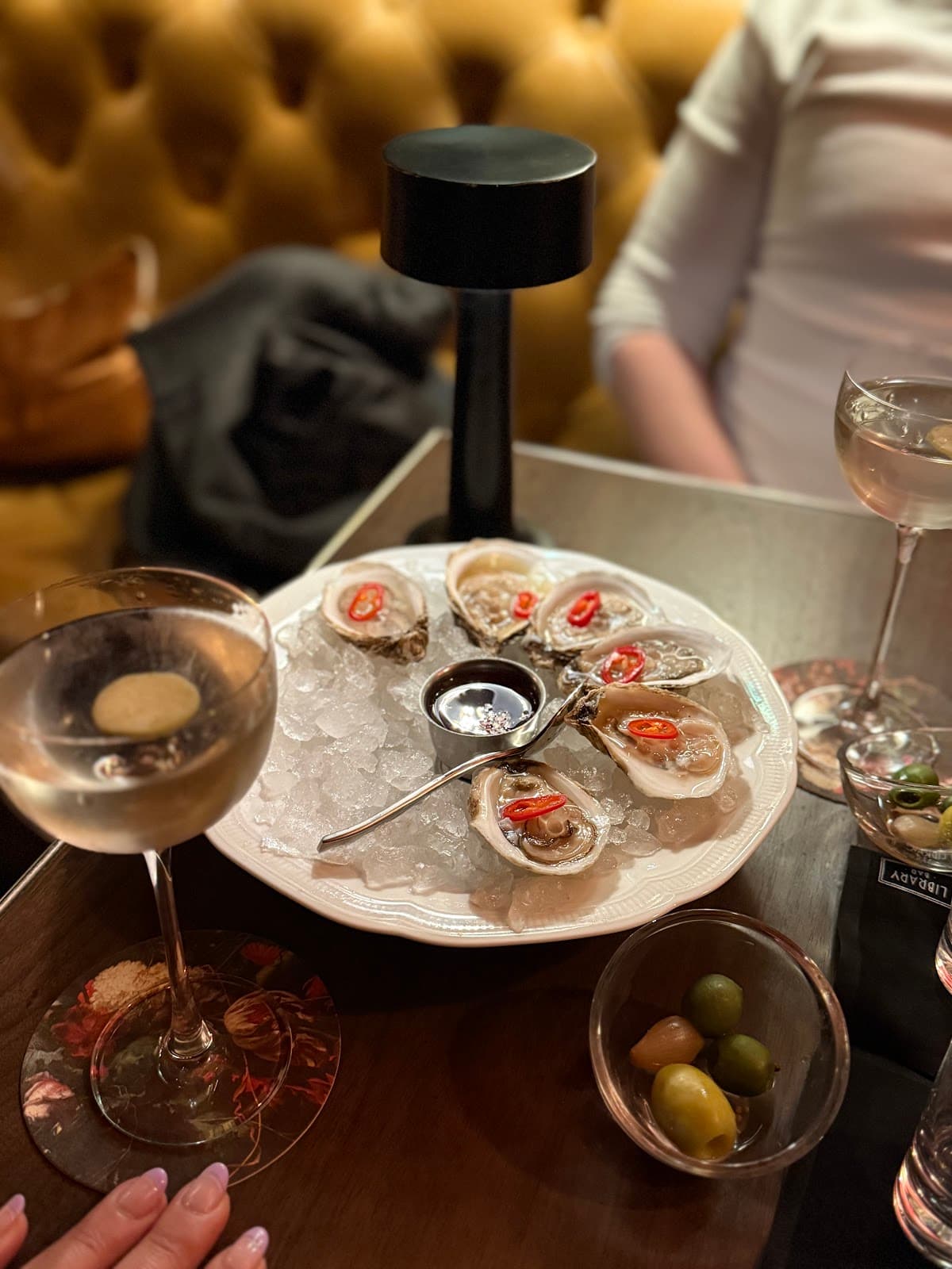 Oysters on ice with a cocktail on a bar table in Toronto