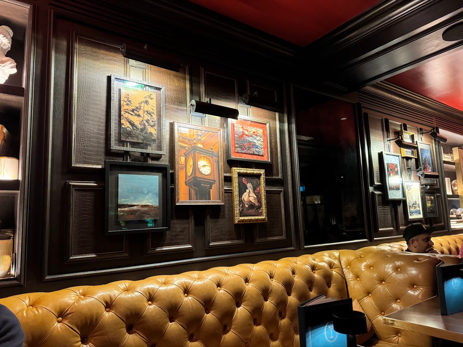 Classy bar interior with leather seating and framed artwork on wooden walls in Toronto