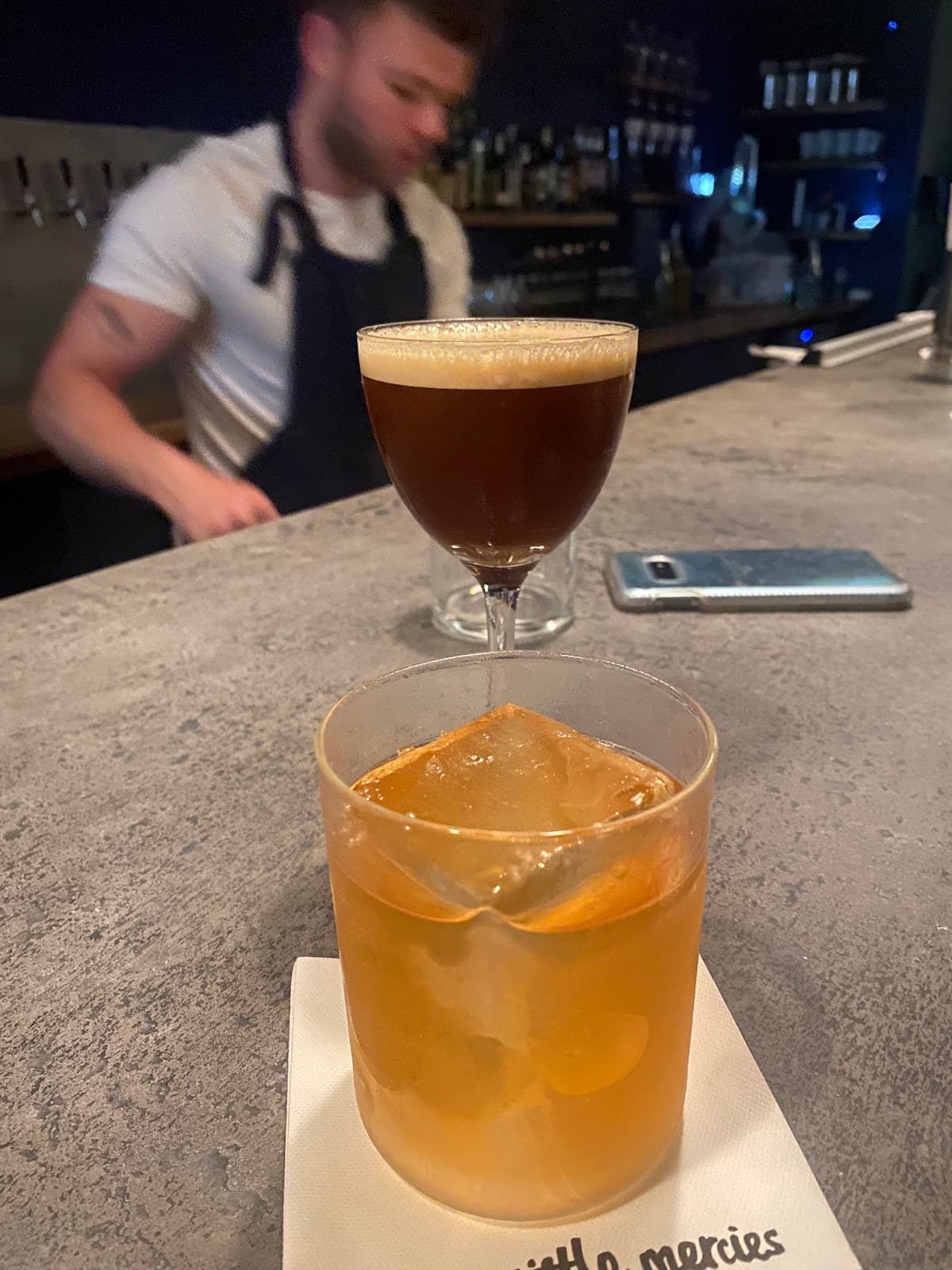 Close-up of two cocktails on a bar counter with bartender in background in London