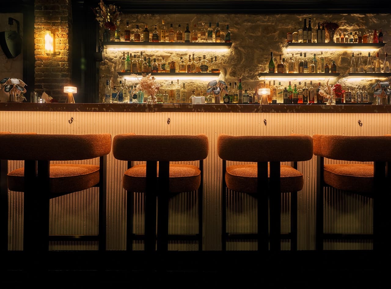 Elegant bar counter with warm lighting and shelves of liquor bottles