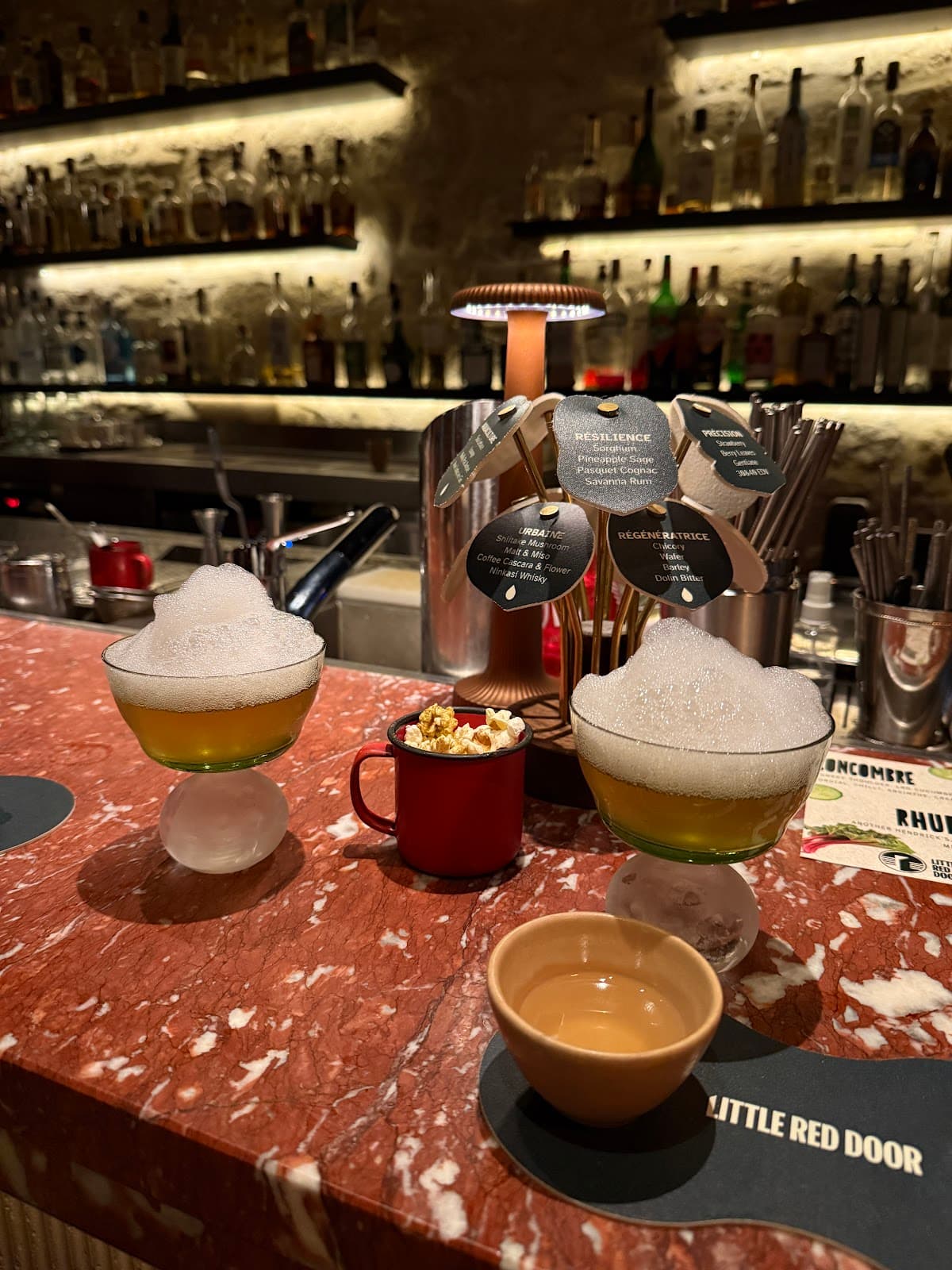 Cocktails on a red marble bar at Little Red Door with foam toppings in Paris