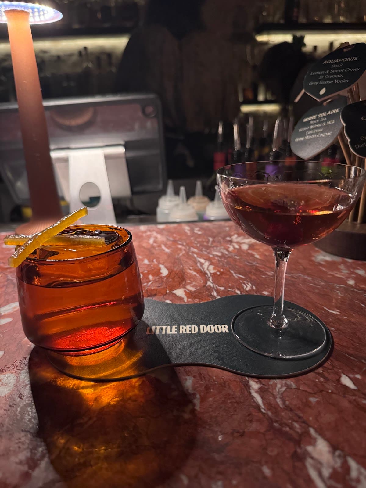 Cocktails on a dimly lit bar at Little Red Door in Paris