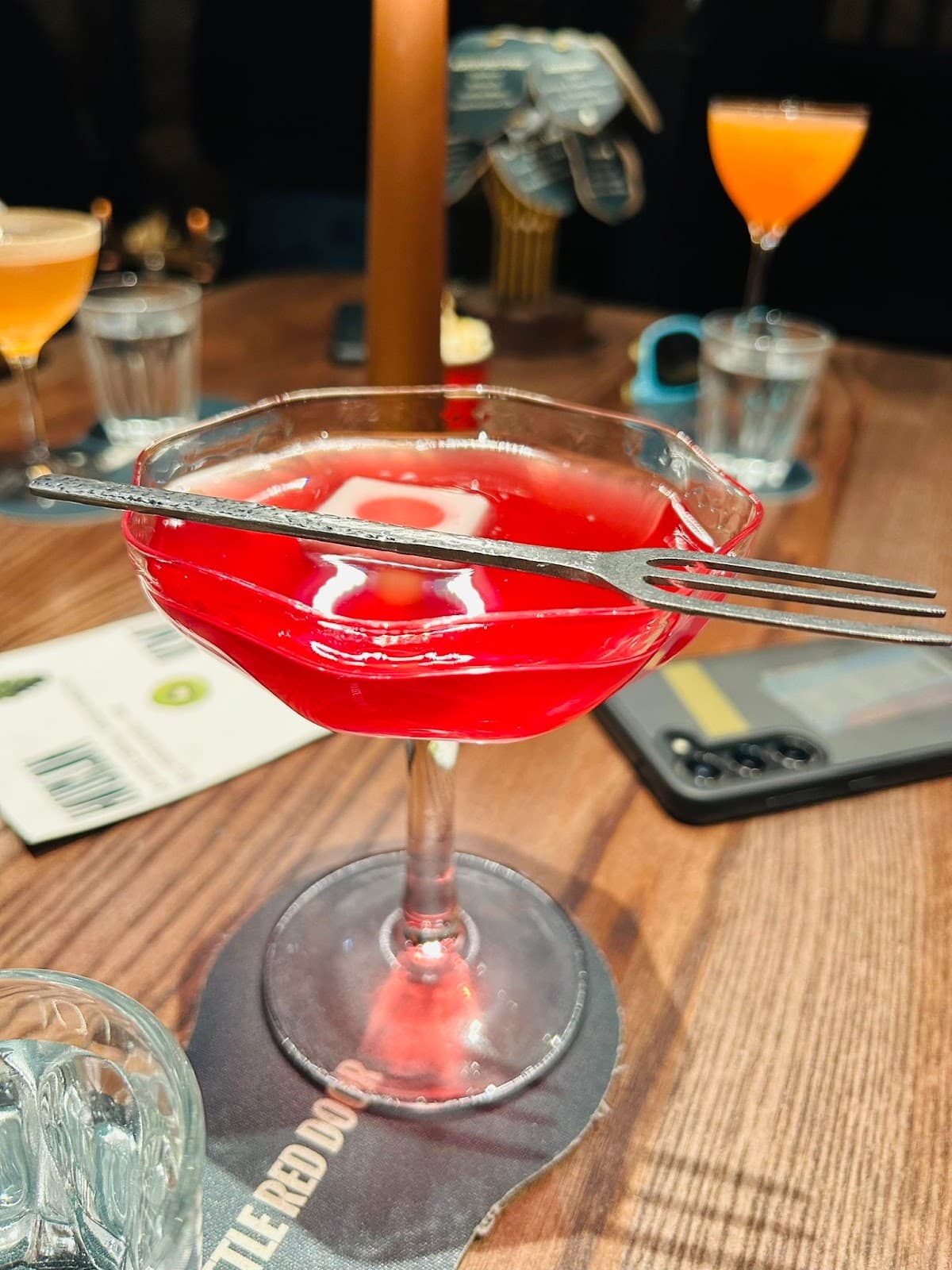 Vibrant red cocktail on a wooden table at Little Red Door in Paris