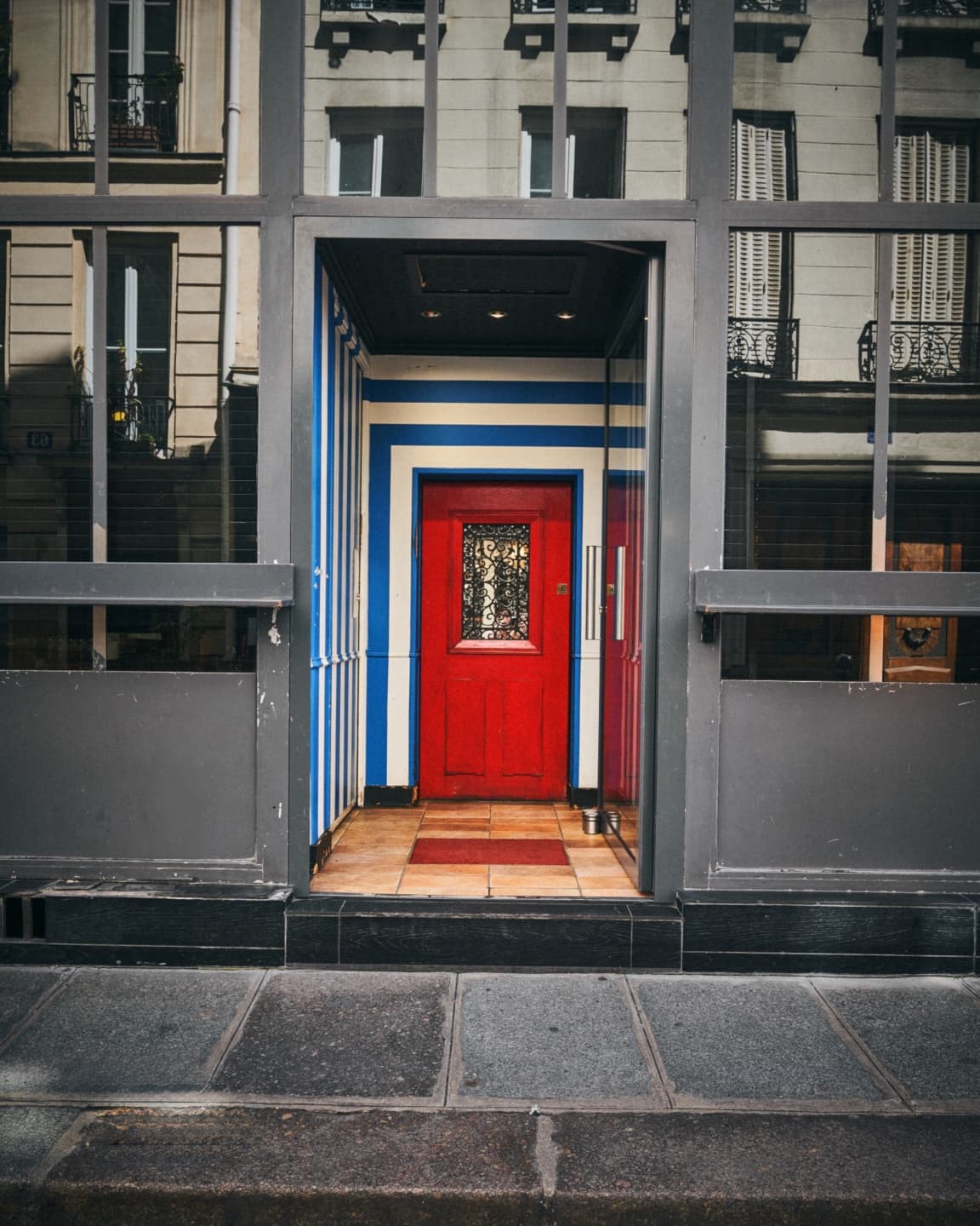 Exterior view with a striking red door and blue striped walls. in Paris