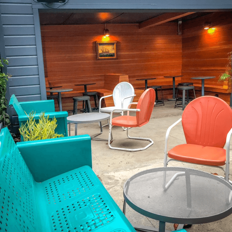 Outdoor seating with colorful chairs and wooden walls at a cocktail bar