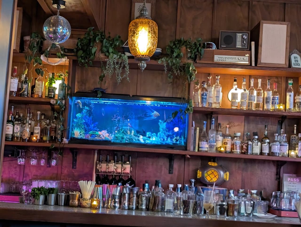 Bar counter with diverse bottles and an aquarium at a cocktail venue in San Francisco