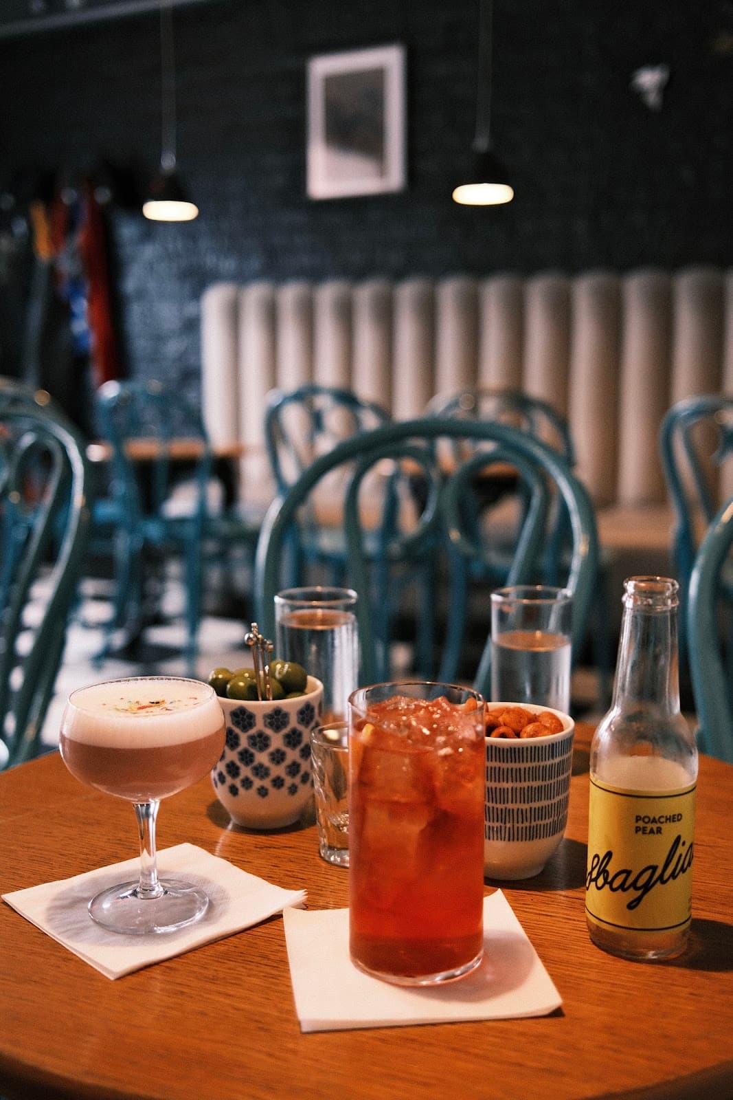 Cocktail and drink setup on a table in a cozy bar with blue chairs in Edinburgh