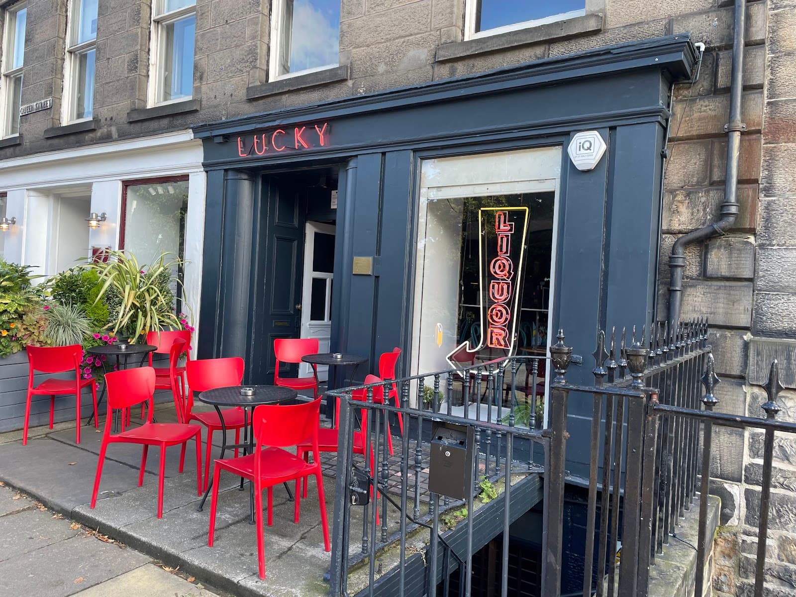 Exterior of Lucky bar with red chairs and neon liquor sign